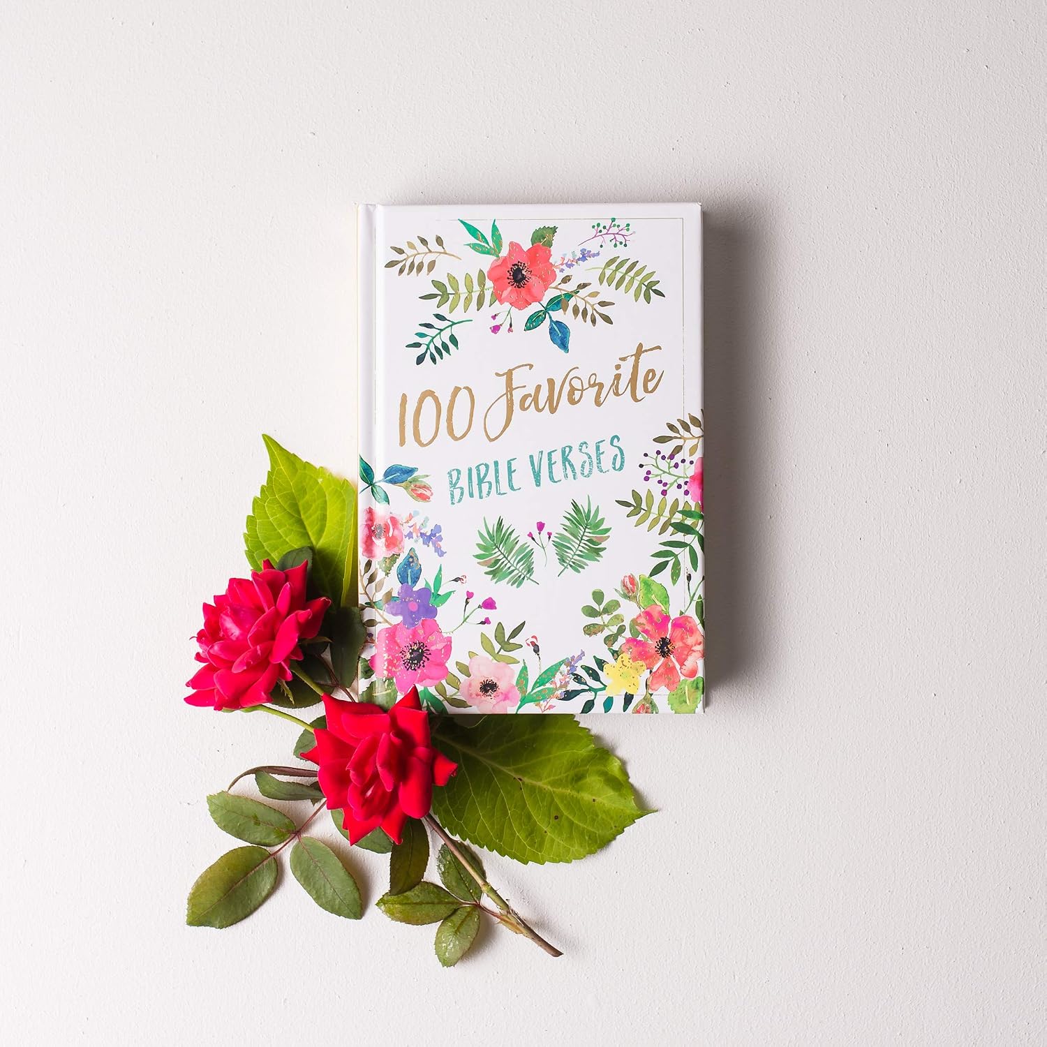 Book titled '100 Favorite Bible Verses' with floral design on a white background