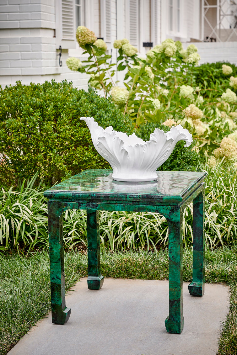 Decorative white bowl on a green table in a garden setting