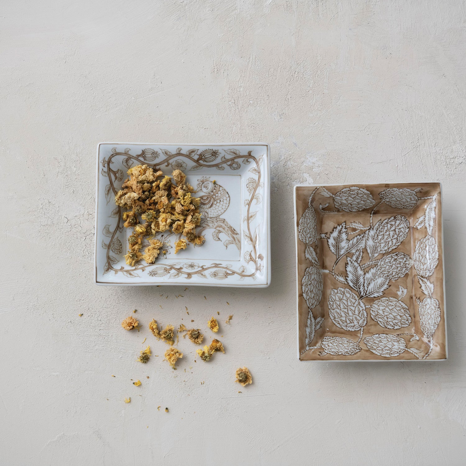 Two decorative boxes with floral embossing on a light gray surface