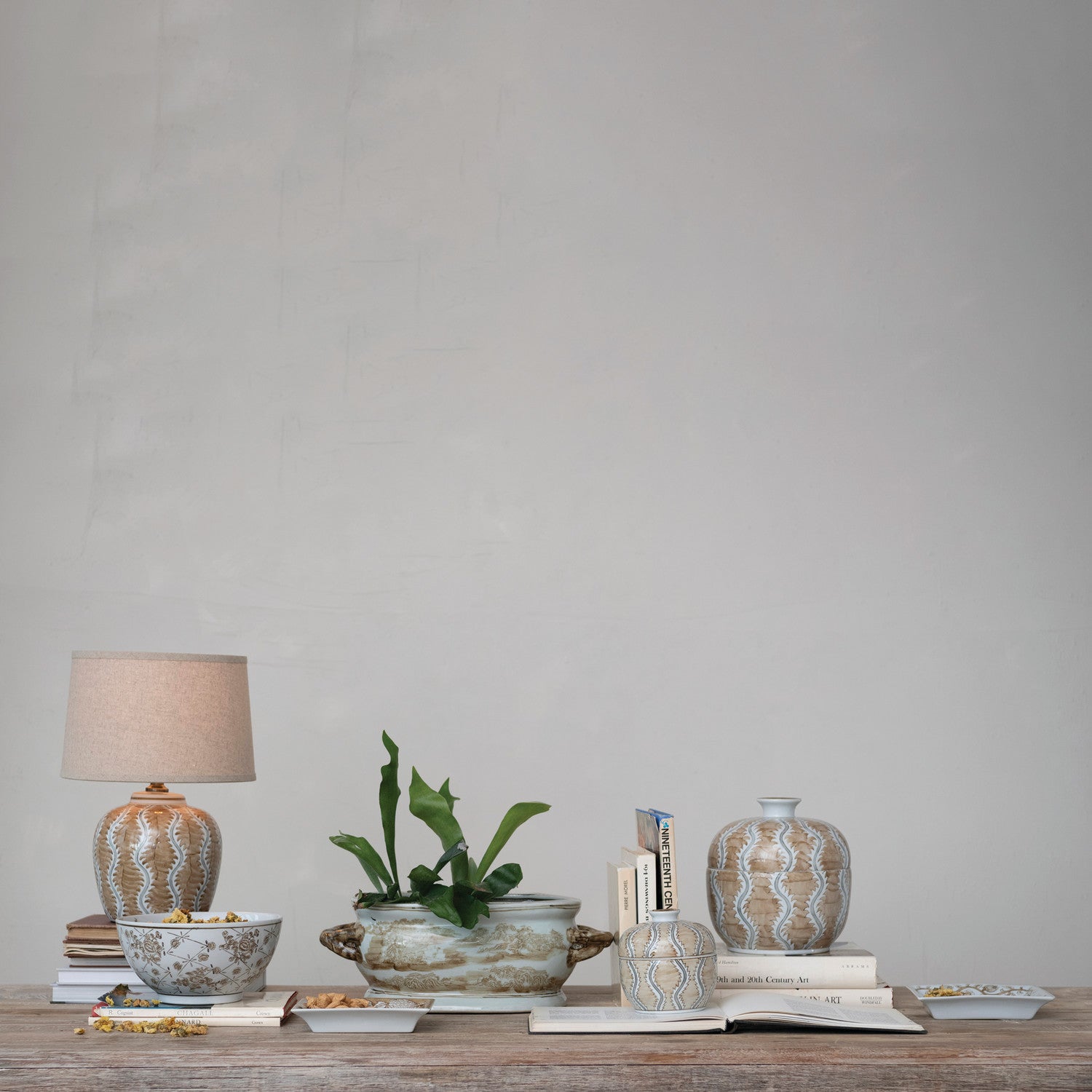 Decorative items including a lamp, plant, and vases on a wooden surface with a plain background