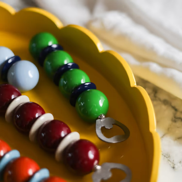 Colorful beaded bracelet with a bottle opener on a yellow plate.
