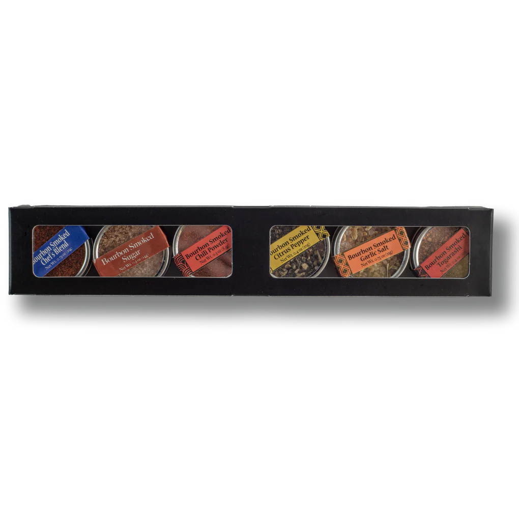Set of six small containers with spices and labels in a black box on a white background