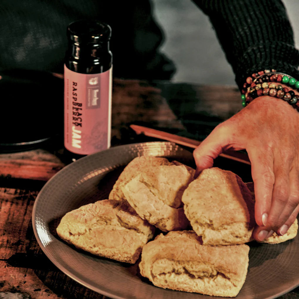 Person reaching for a biscuit on a plate with a bottle in the background