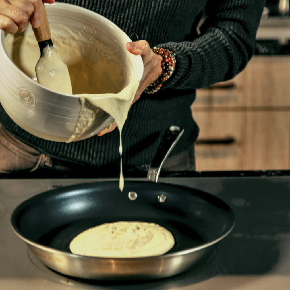 Person pouring pancake batter into a frying pan