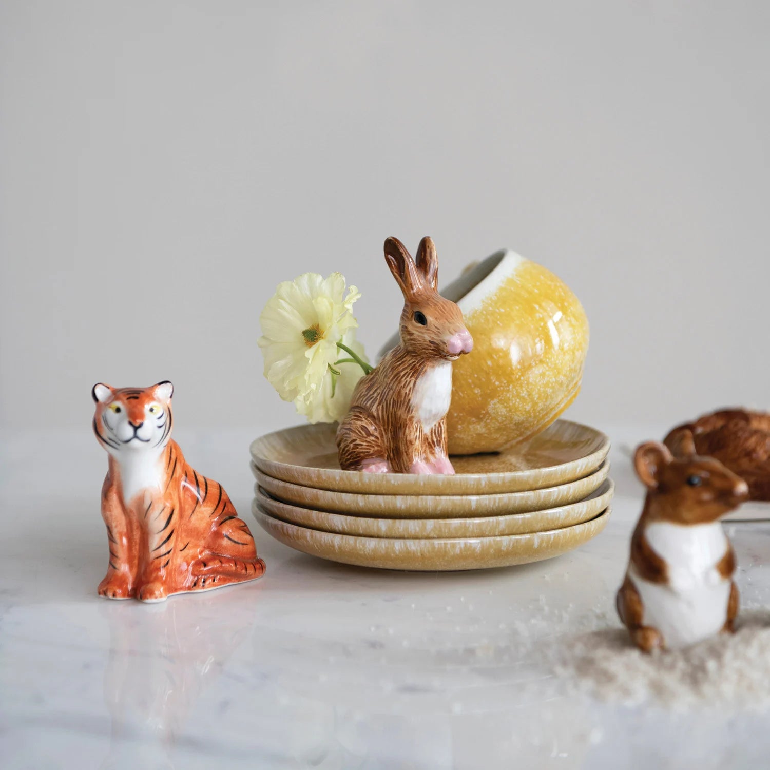 Set of ceramic animal figurines including a tiger, rabbit, and mouse on a marble surface with a neutral background.