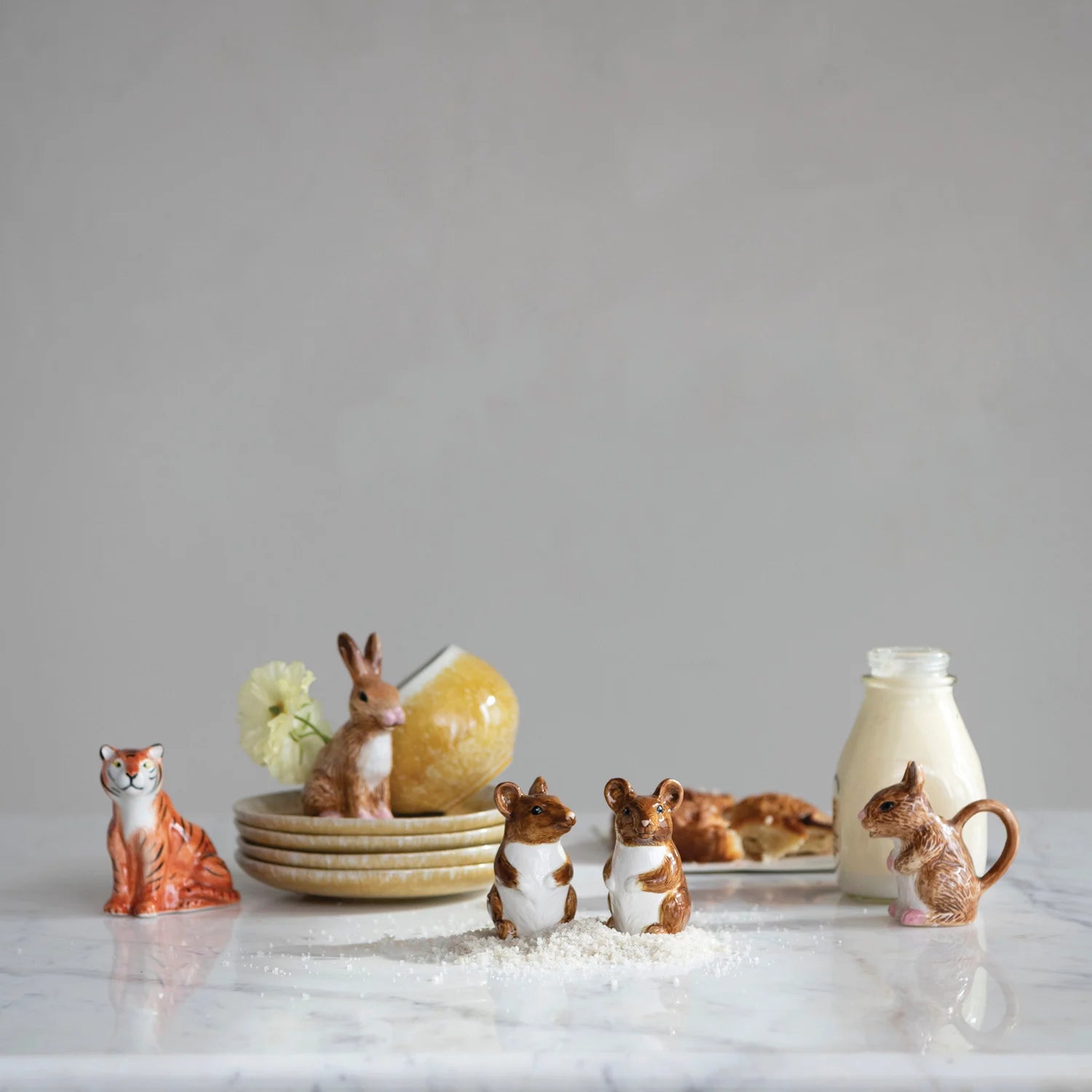 Set of small animal figurines on a marble surface with a neutral background