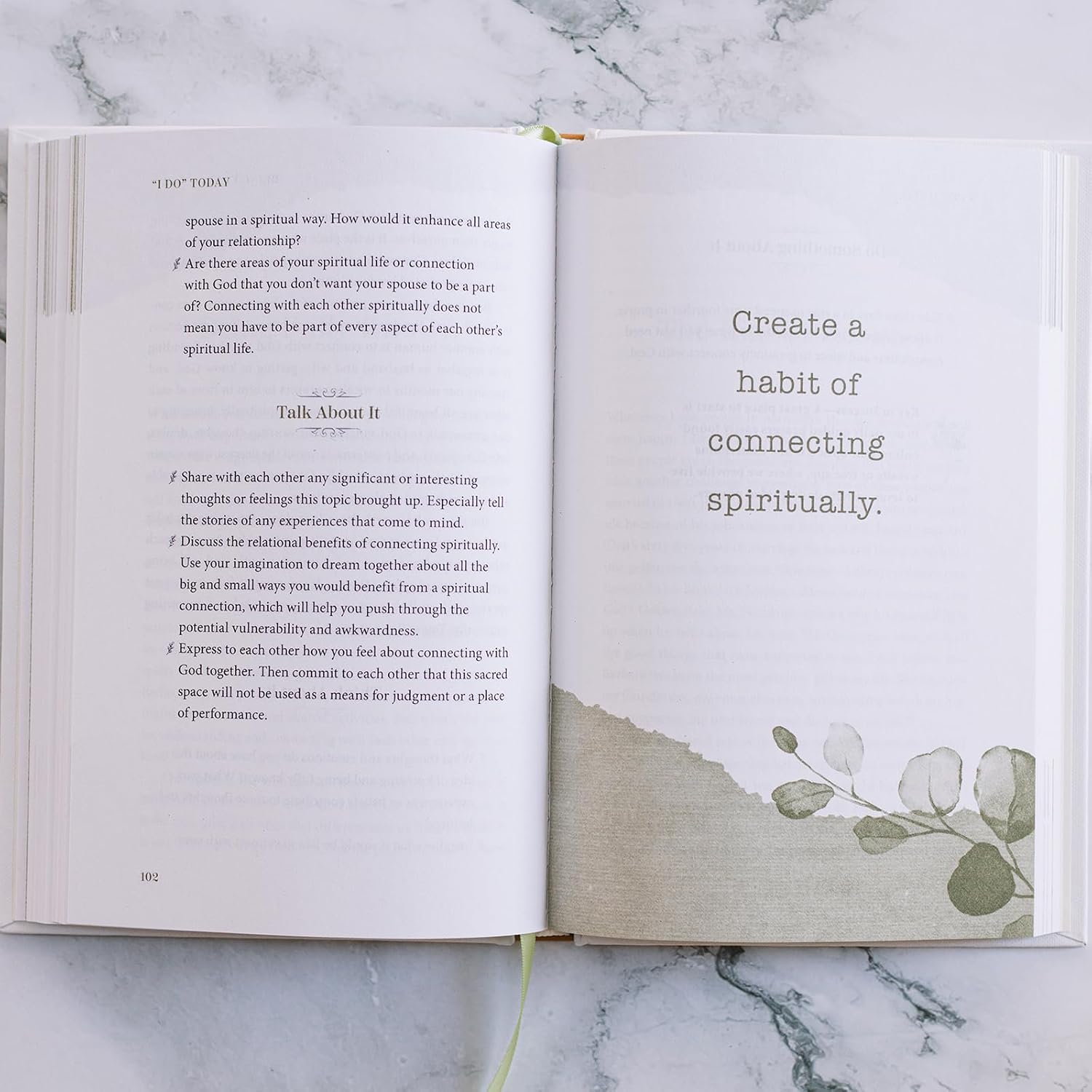 Open book with text and a leaf design on a marble surface