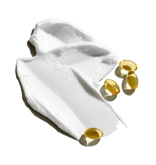 White cream with gold capsules on a white background