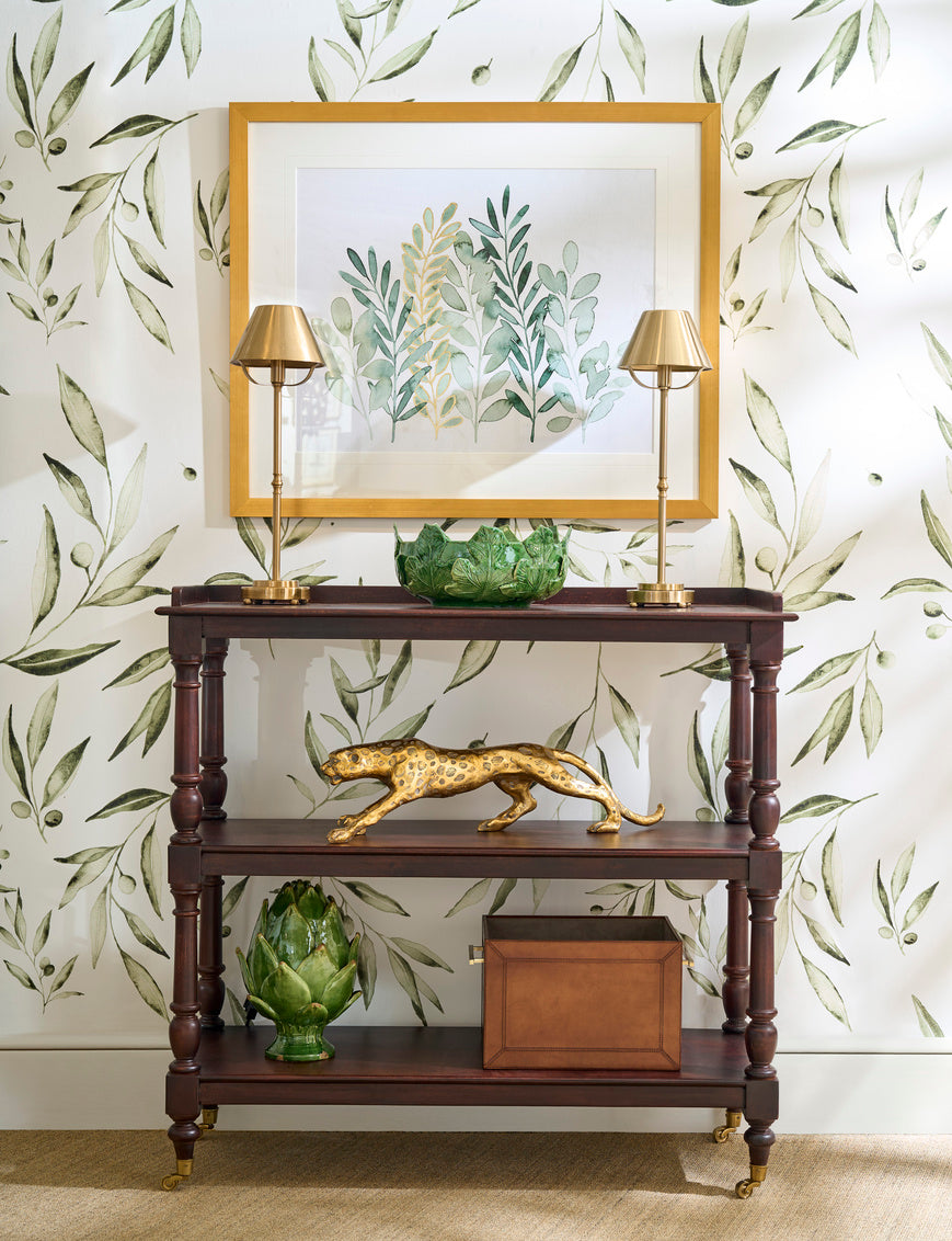 Decorative console table with gold accents against a leaf-patterned wall.