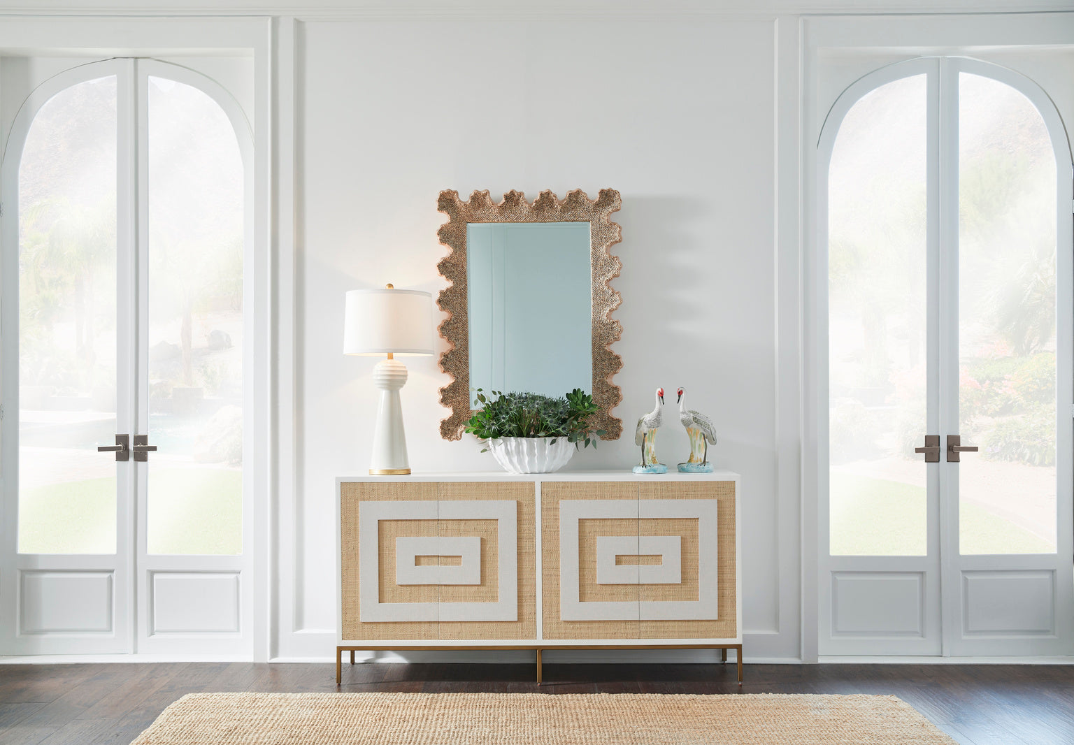Beige sideboard with decorative items in a room with large windows.
