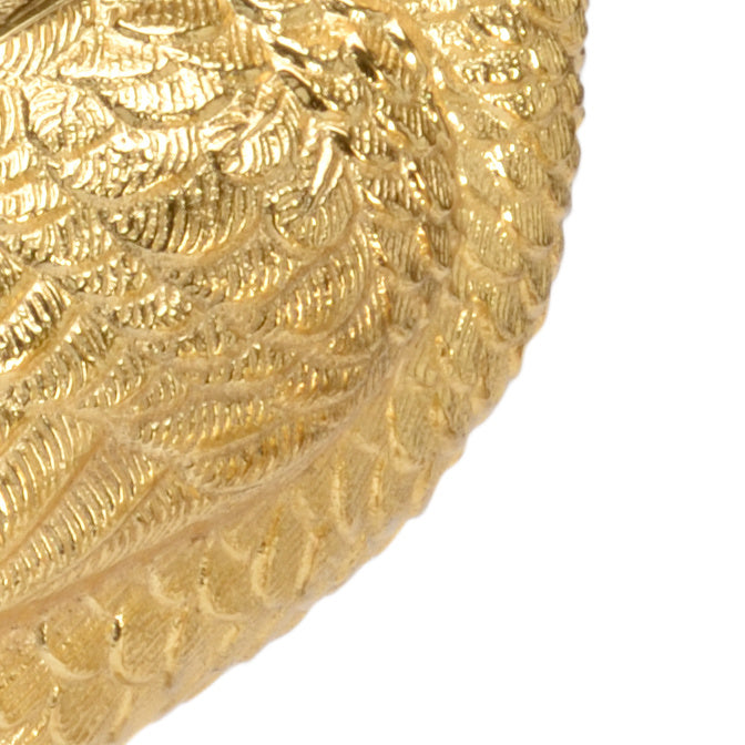 Close-up of a gold decorative peacock with intricate patterns on a white background