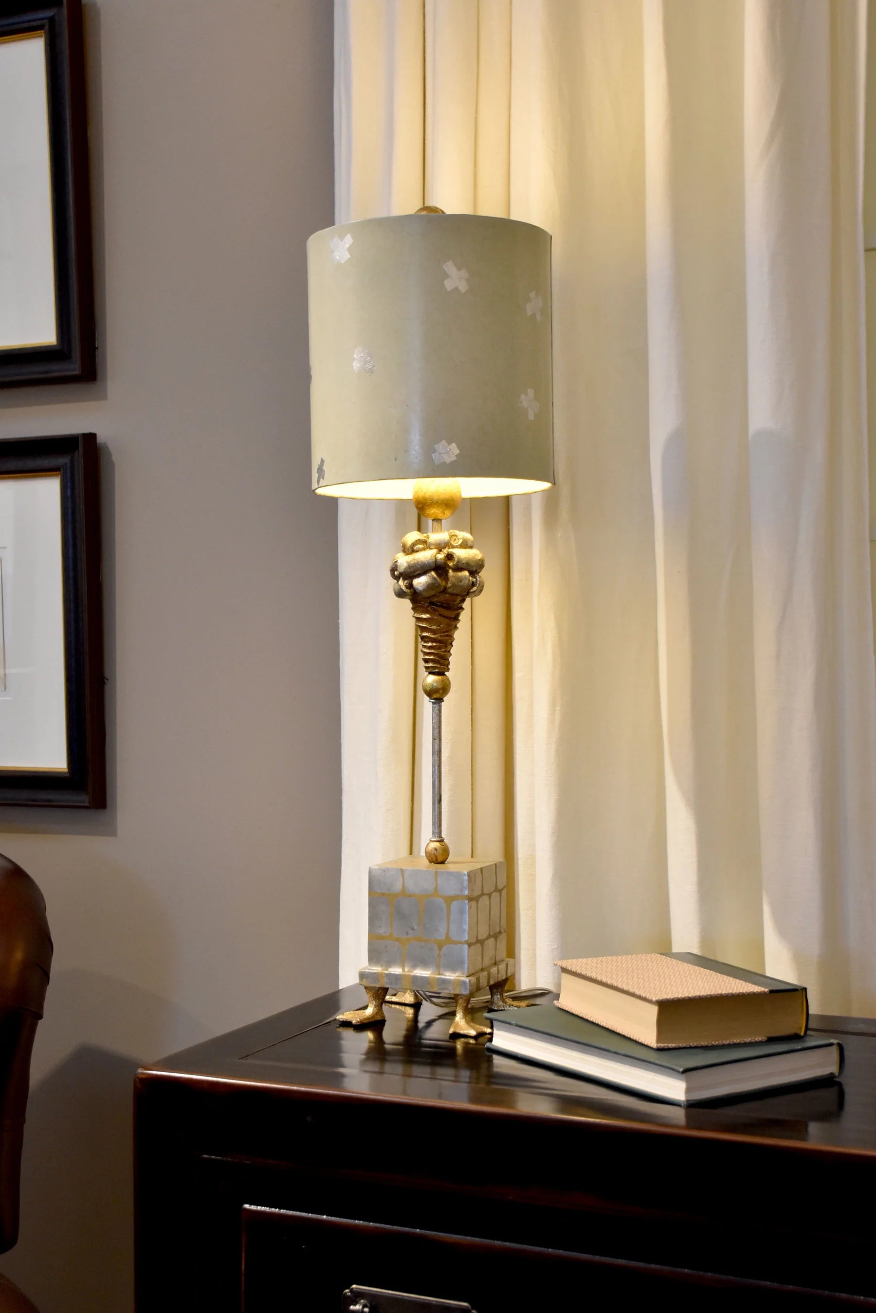 Decorative lamp with a gold base on a wooden surface next to a curtain