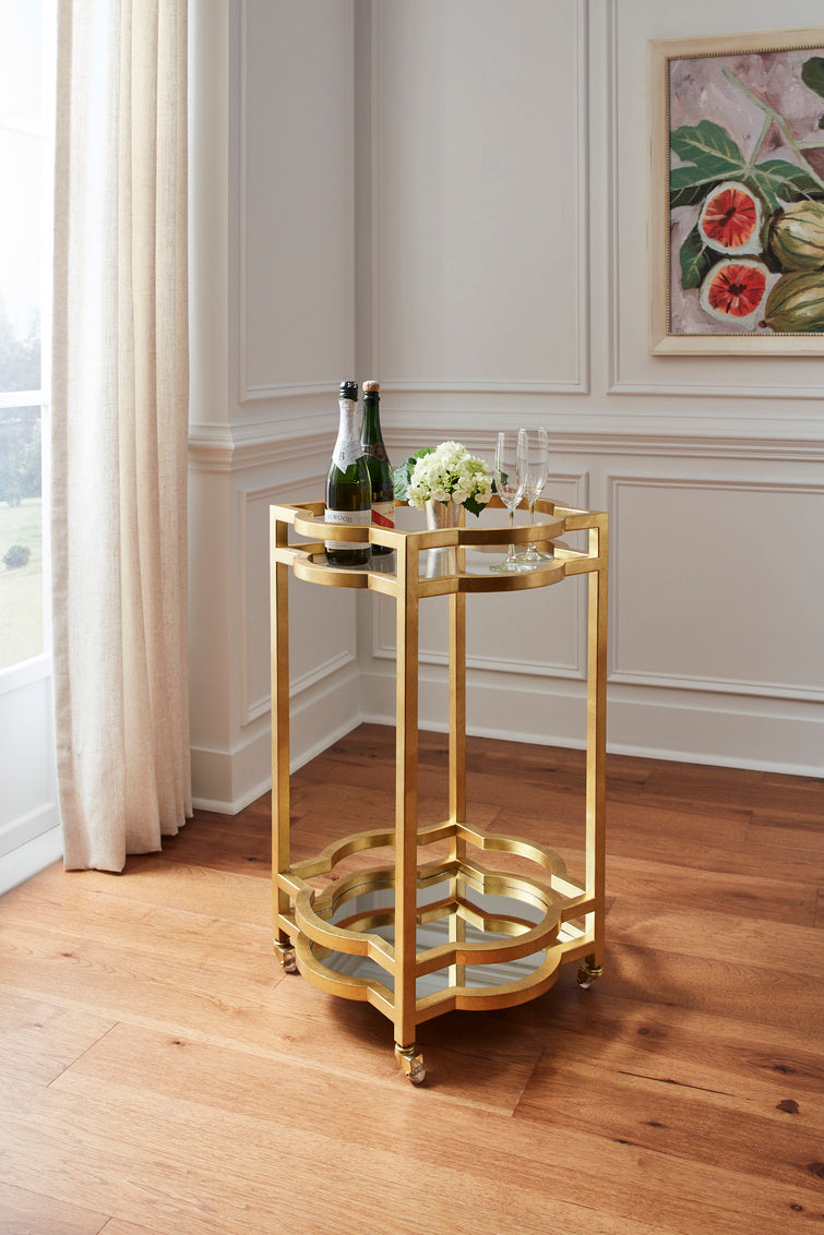 Gold bar cart with champagne and flowers in a stylish room.