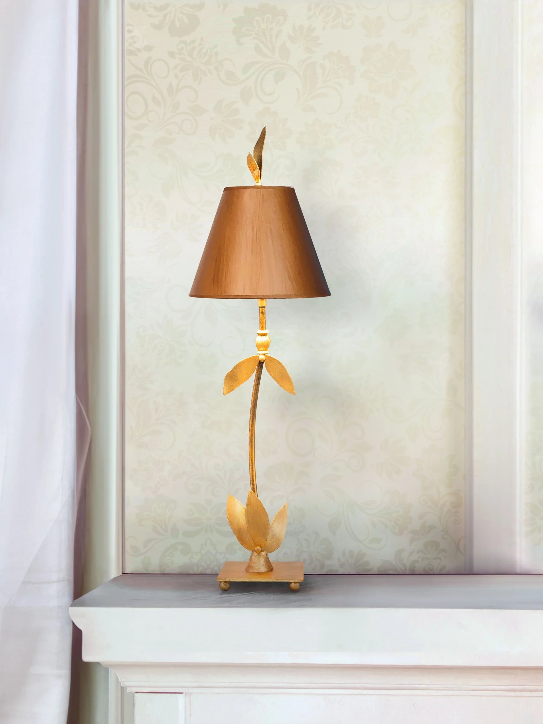 Decorative table lamp with a unique design on a white surface against a light-colored wall.