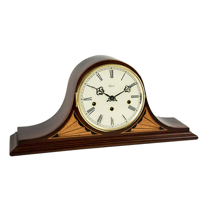 Wooden mantel clock with white face and black hands on a white background