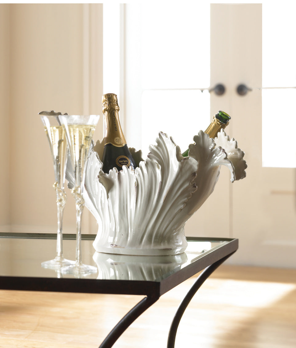 Decorative white leaf-shaped wine cooler with bottles inside, placed on a black table.