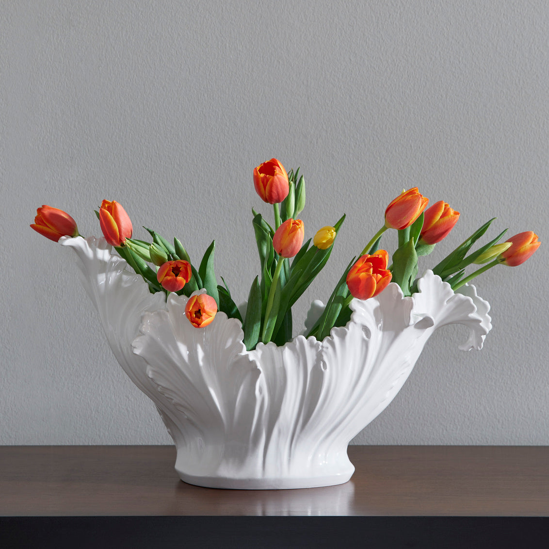 White ceramic bowl filled with orange tulips on a gray background