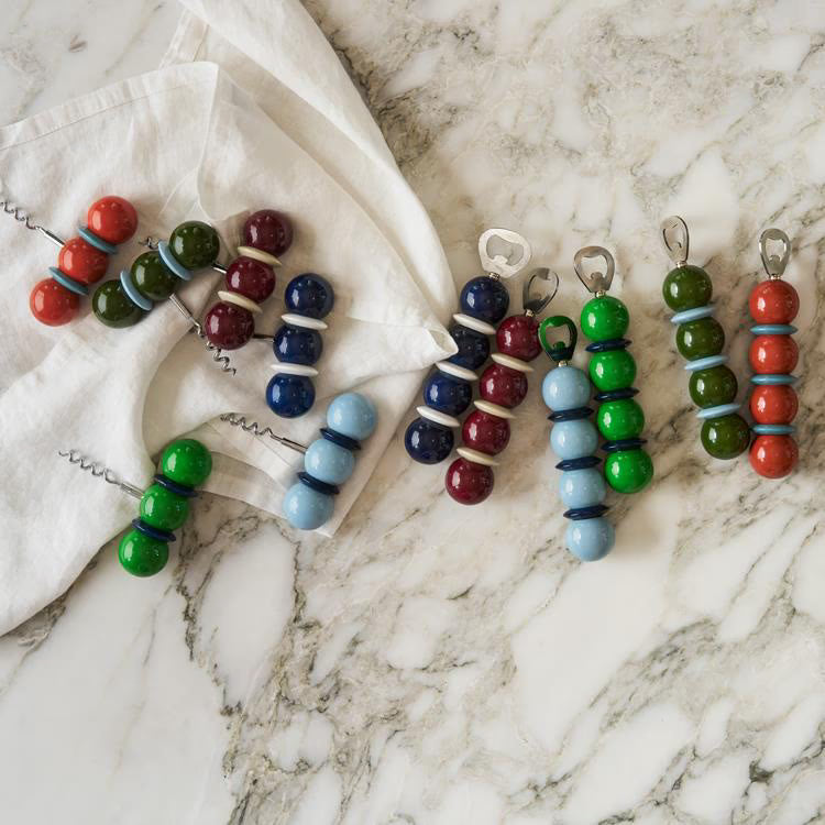 Colorful beaded corkscrews on a marble surface with a white cloth.