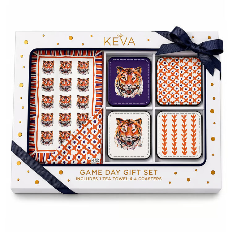 Keva Game Day Gift Set containing a 1 tea towel and 4 coasters, presented in a white gift box with gold polka dots and a navy ribbon. The tea towel features a repeating orange and white tiger face pattern, while the coasters feature matching tiger and geometric patterns.