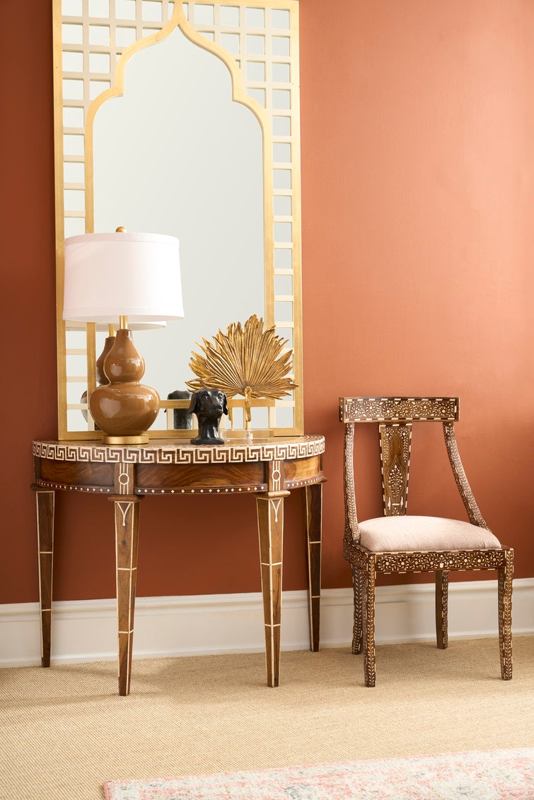 Decorative table with lamp and chair against a brown wall