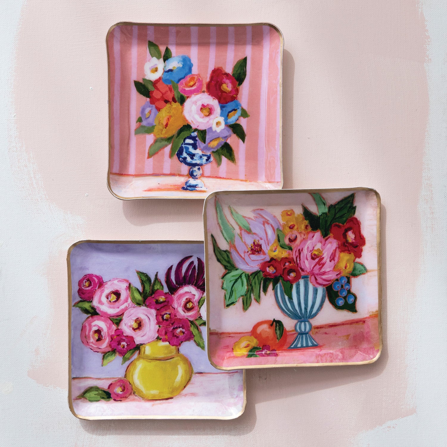 Three decorative trays with floral designs on a light pink background