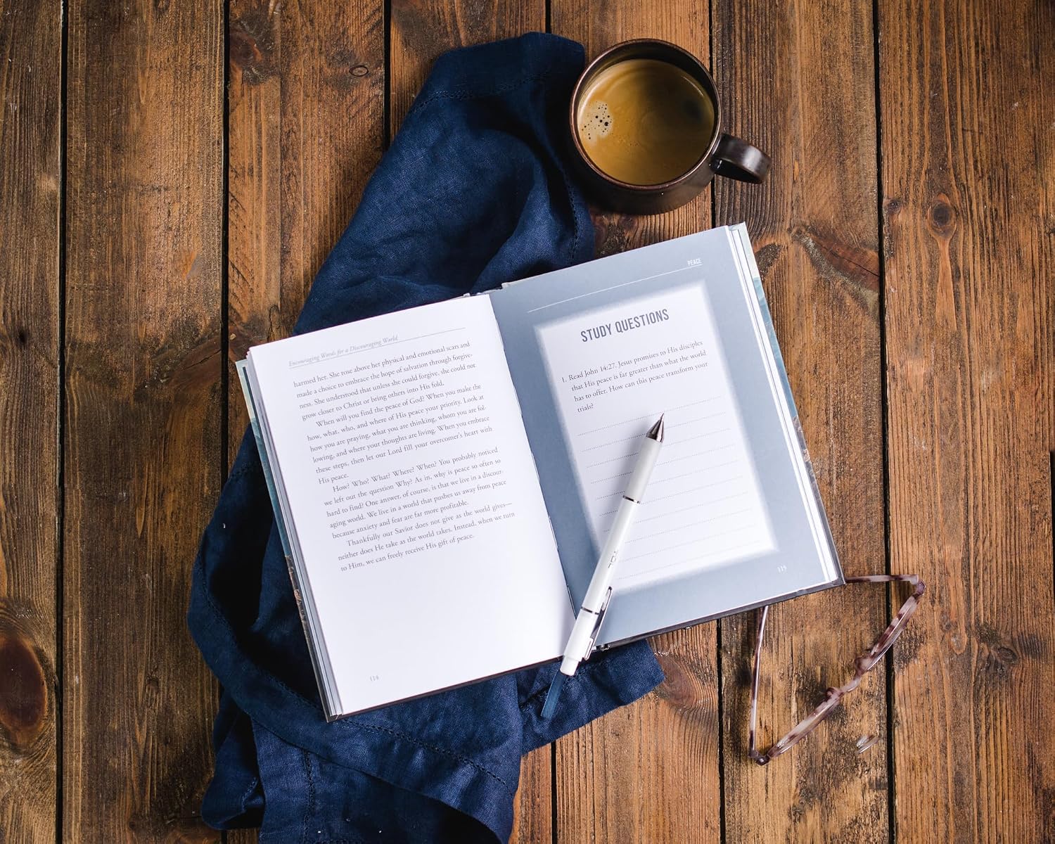Open book with a pen and coffee cup on a wooden surface