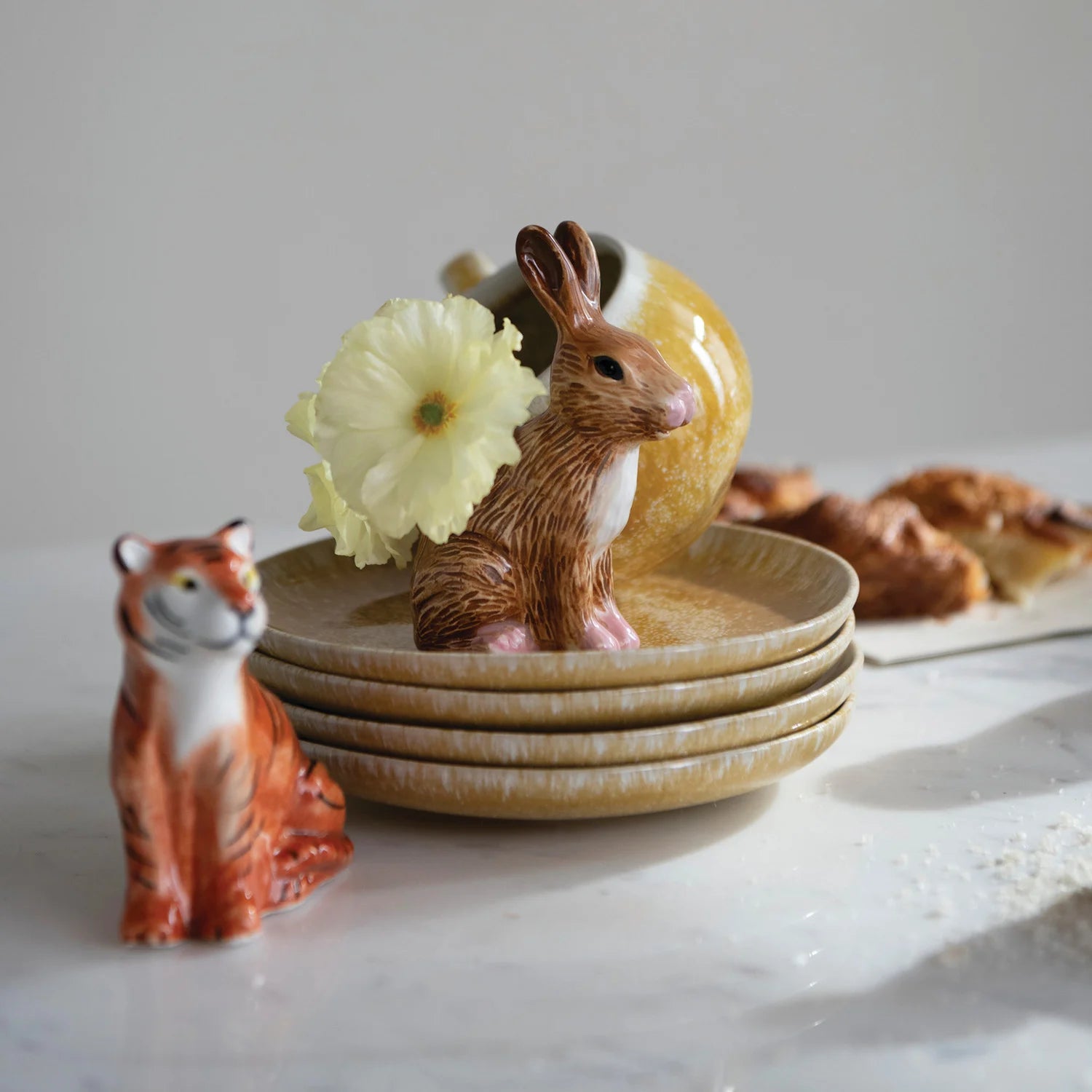 Set of ceramic plates with animal figurines on a light surface