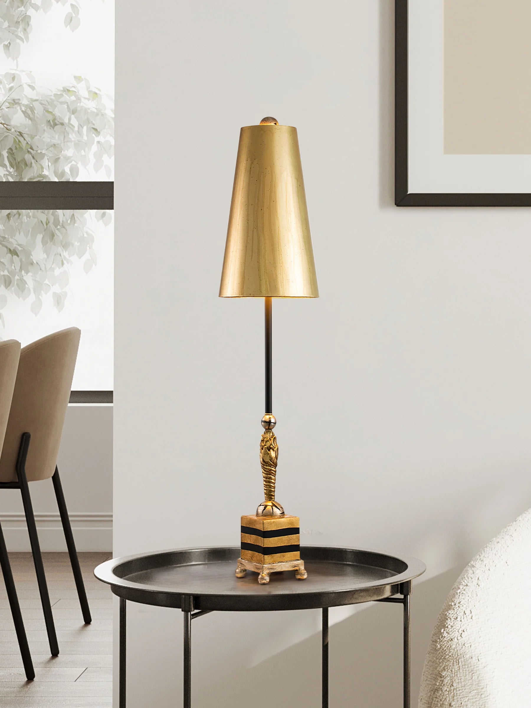 Gold table lamp on a round black table with a neutral background