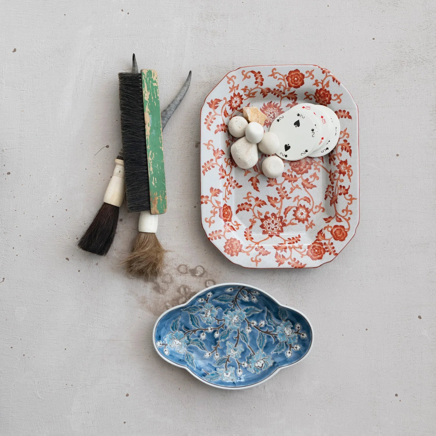 Two ceramic dishes, one with floral pattern and the other with blue floral design, on a light gray surface.