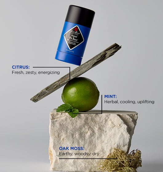 Blue deodorant stick with a lime, stick, and moss on a gray background