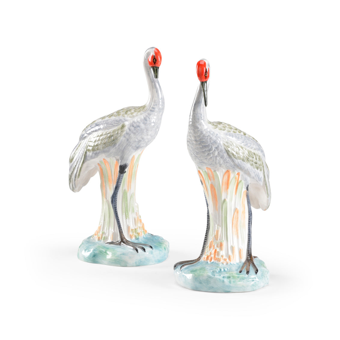 Two ceramic cranes with red heads on a white background