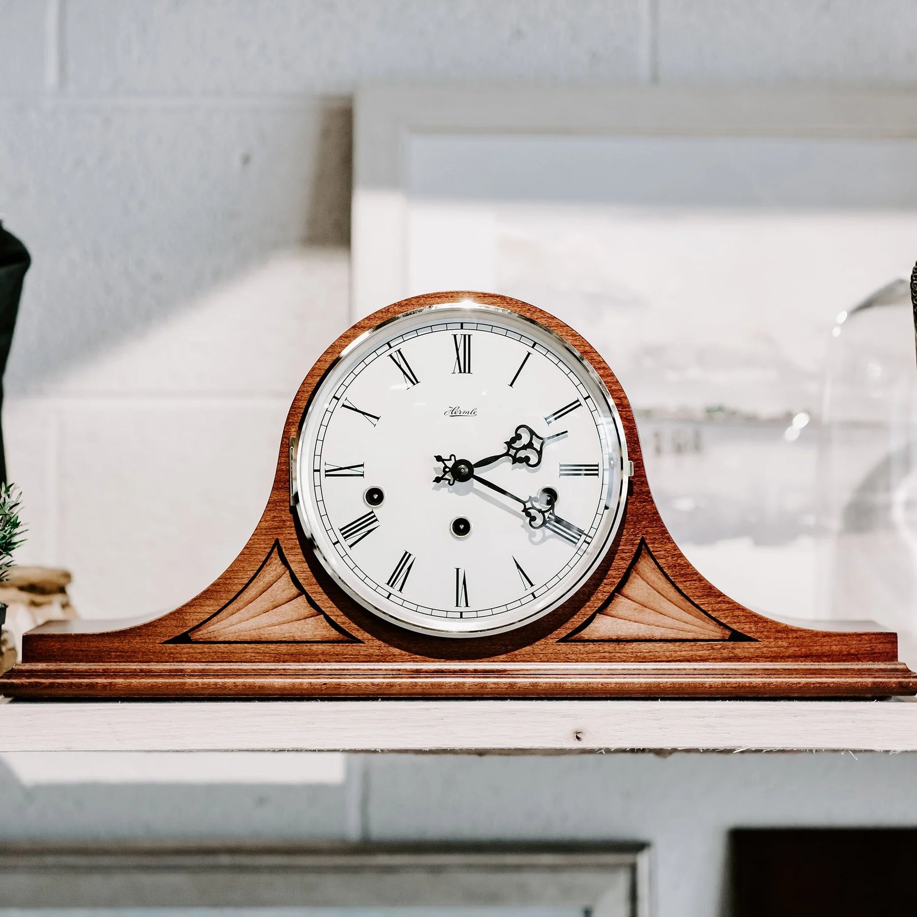 Wooden clock with white face and black hands on a white surface
