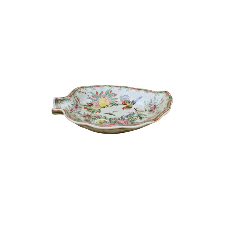A small leaf-shaped ceramic dish with a handle, decorated with a colorful hand-painted floral and bird pattern on a white background.